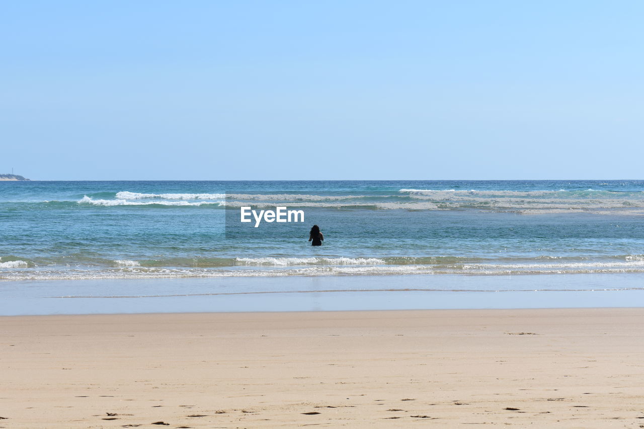 Woman at beach against clear sky