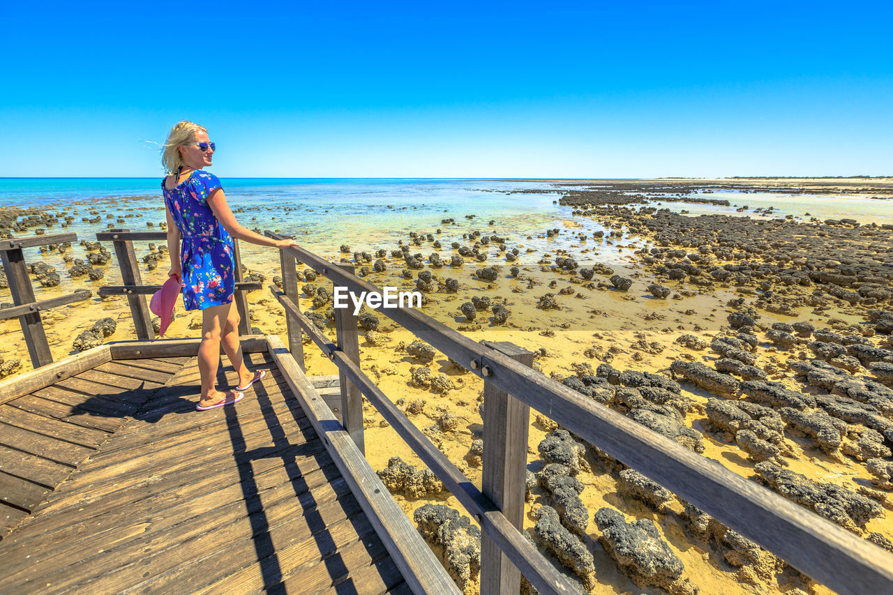 Woman standing on wood against clear sky