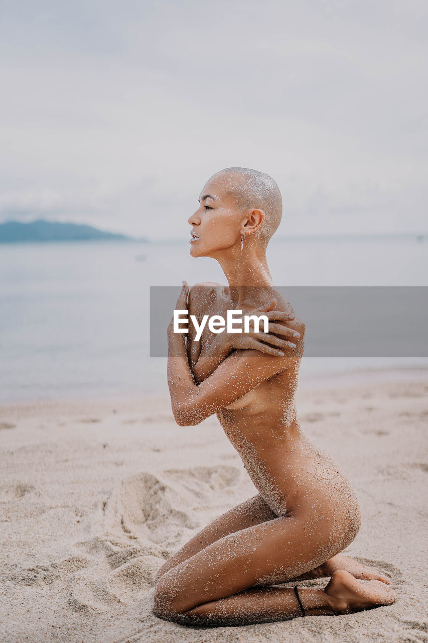 Low section of woman sitting at beach