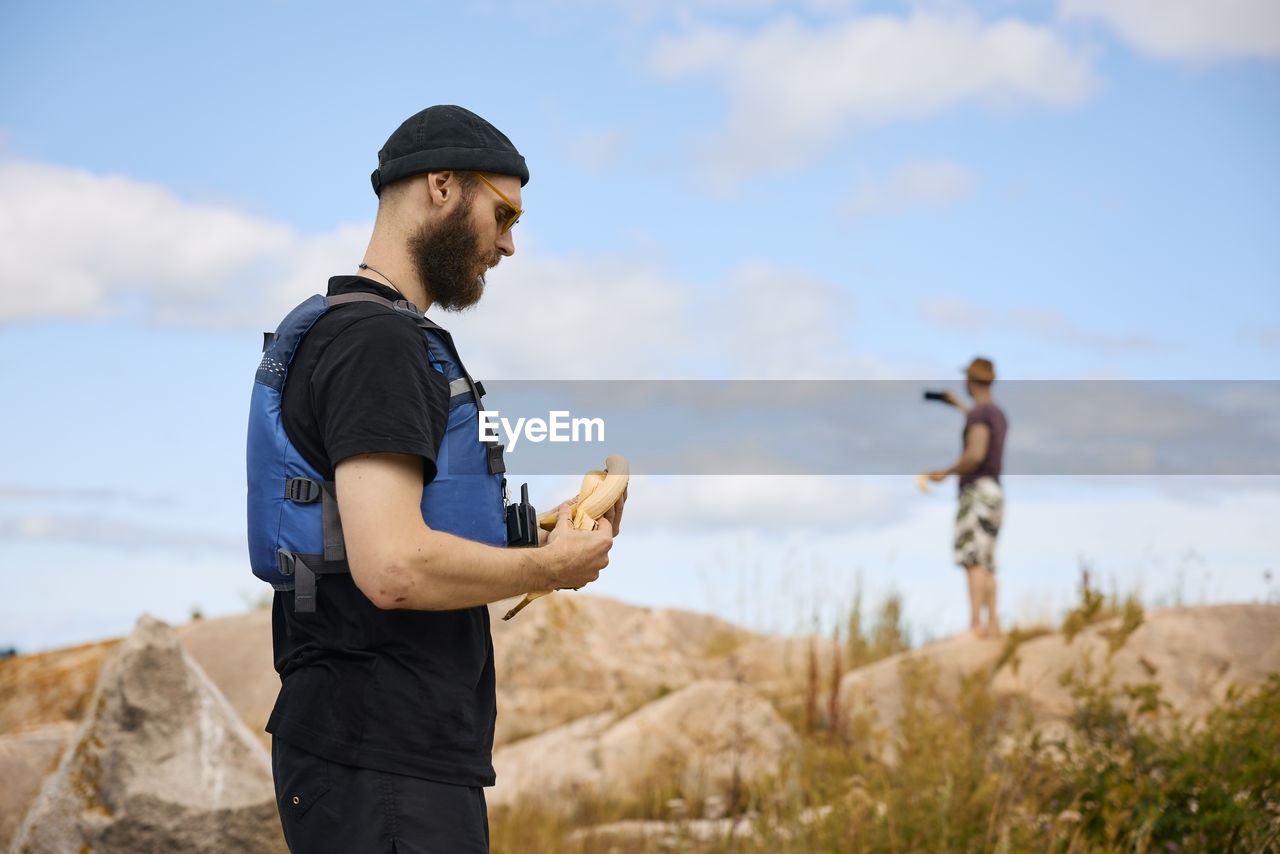 Man standing on coast and peeling banana