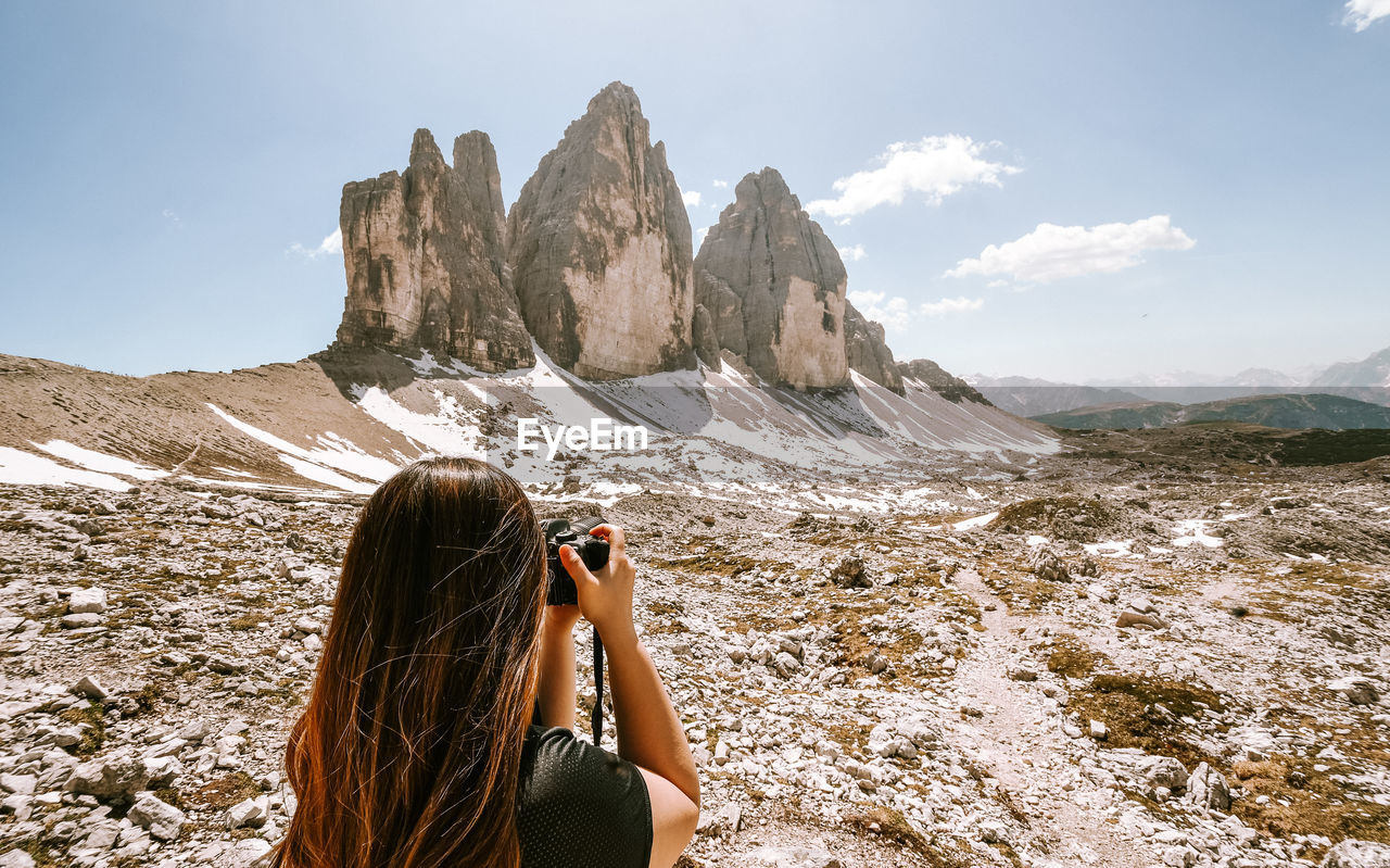 Rear view of woman photographing mountain range 