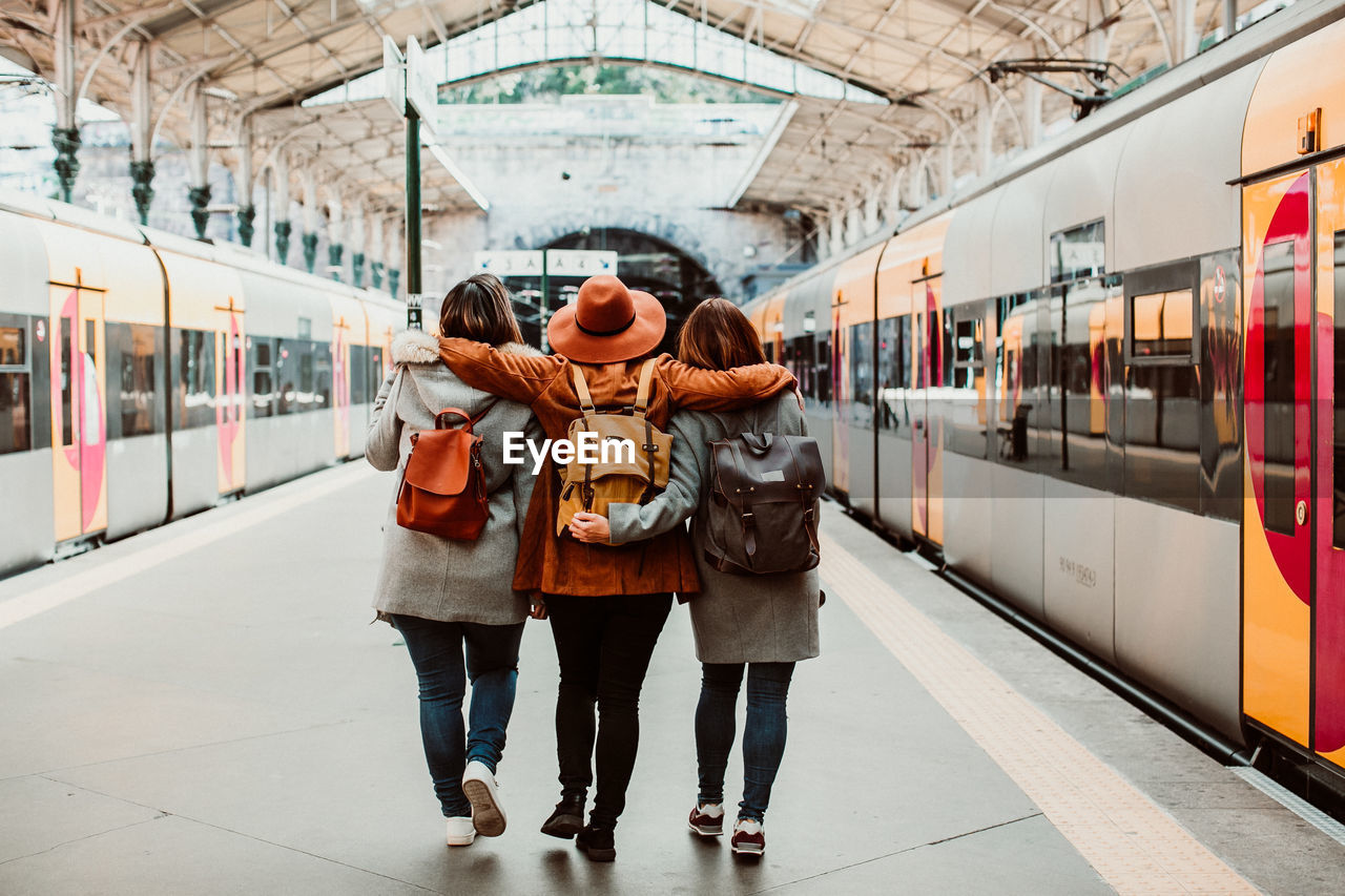 Rear view of friends walking at station