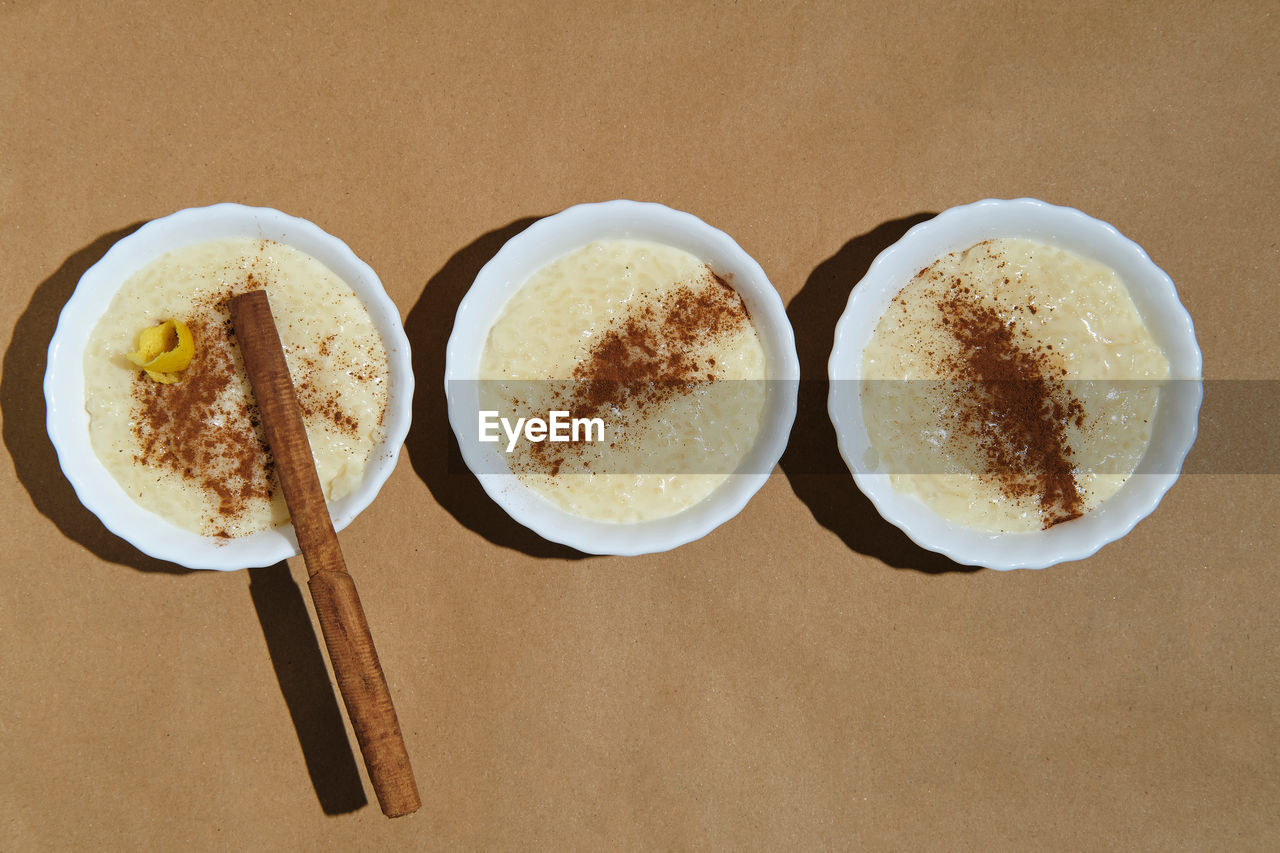 Zenithal plane of three rice pudding desserts on a brown background