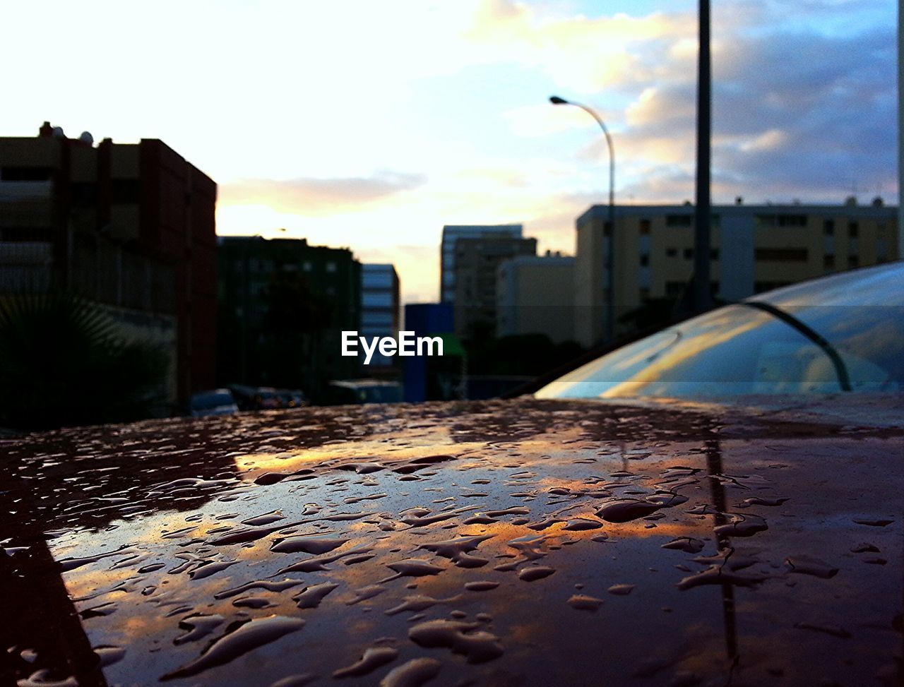 Water drops on car hood with buildings in background