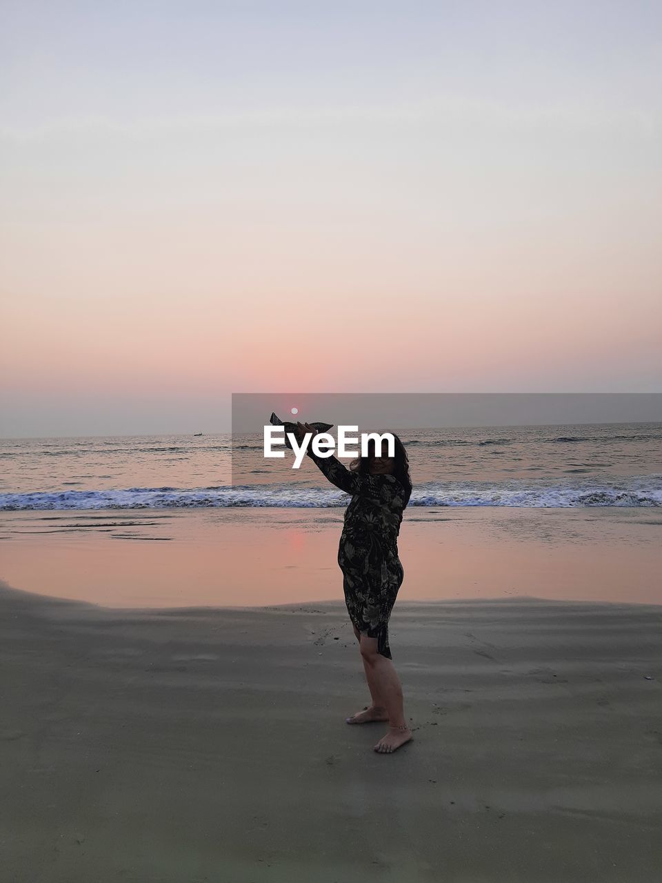 Full length of woman on beach against sky during sunset