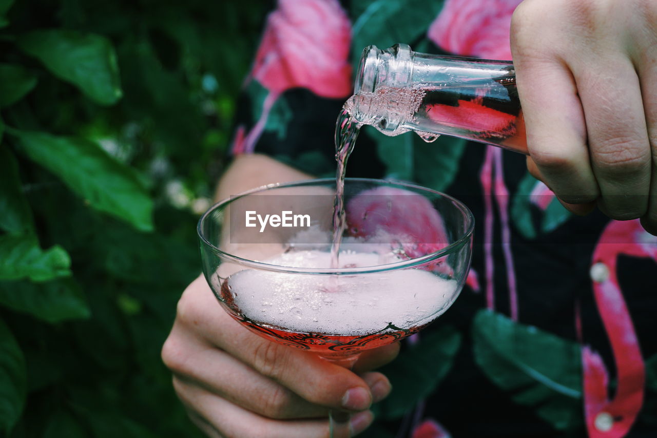 Midsection of young man serving rosé wine