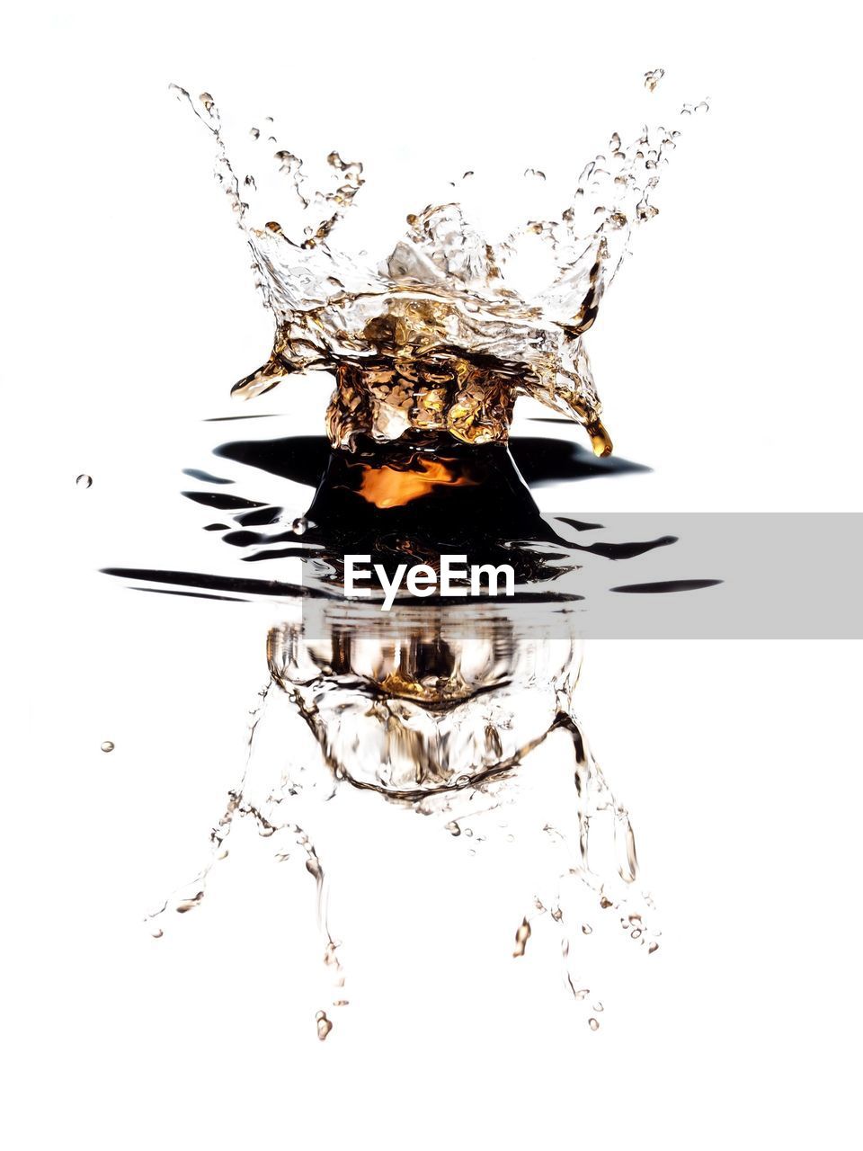 Close-up of drop falling on water against white background