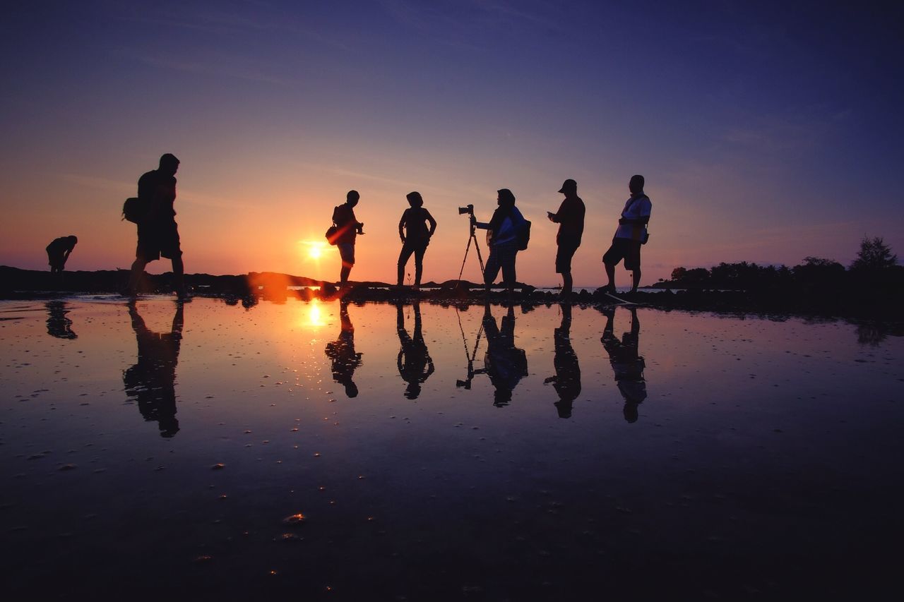 Silhouette people standing on beach during sunset