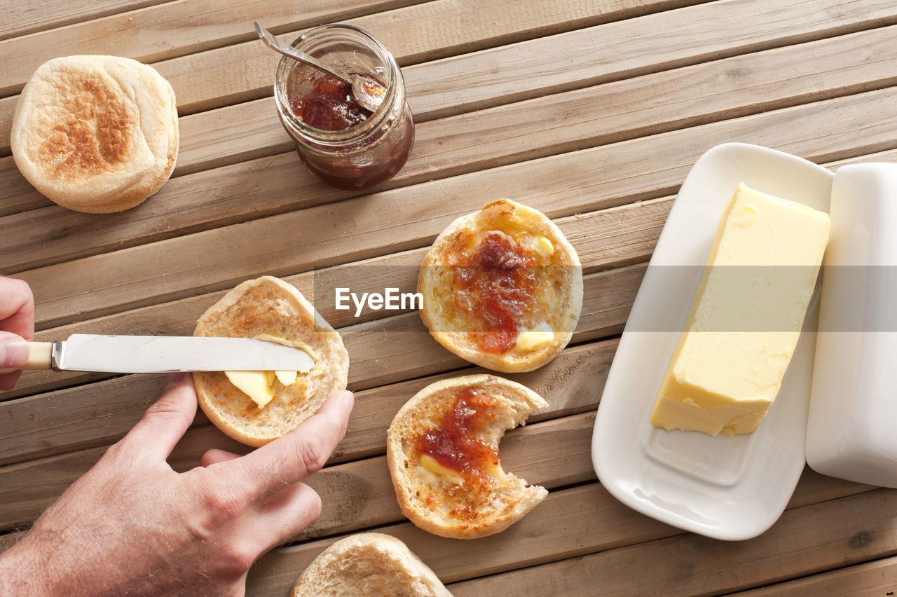 Man buttering a freshly baked toasted crumpet for breakfast from a large pat of butter