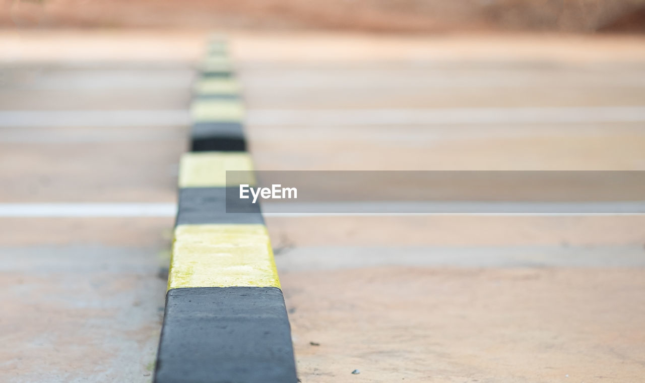 Row of concrete wheel stopper in black and yellow color striped with selective soft focus.