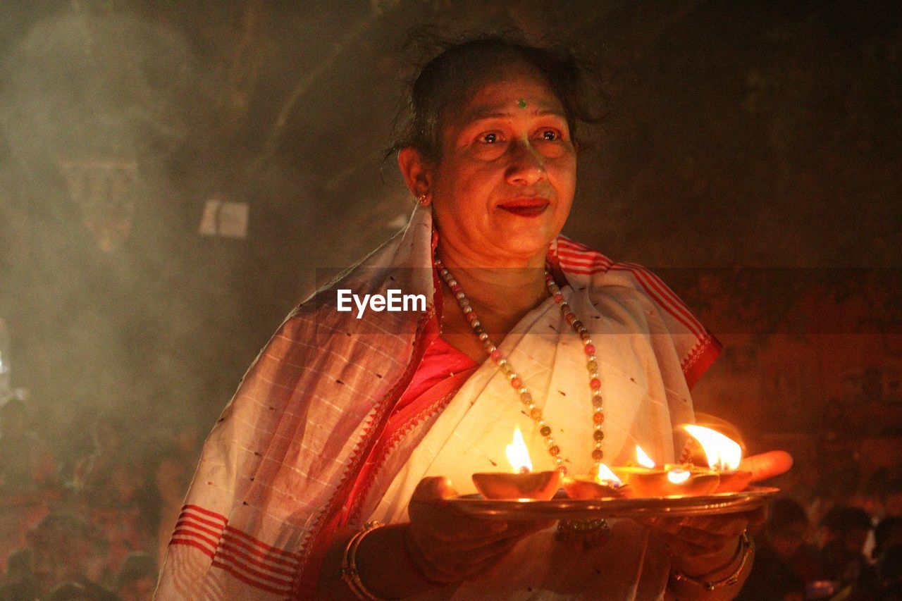 Women holding dia-oil lamp on hand in a smokey environment