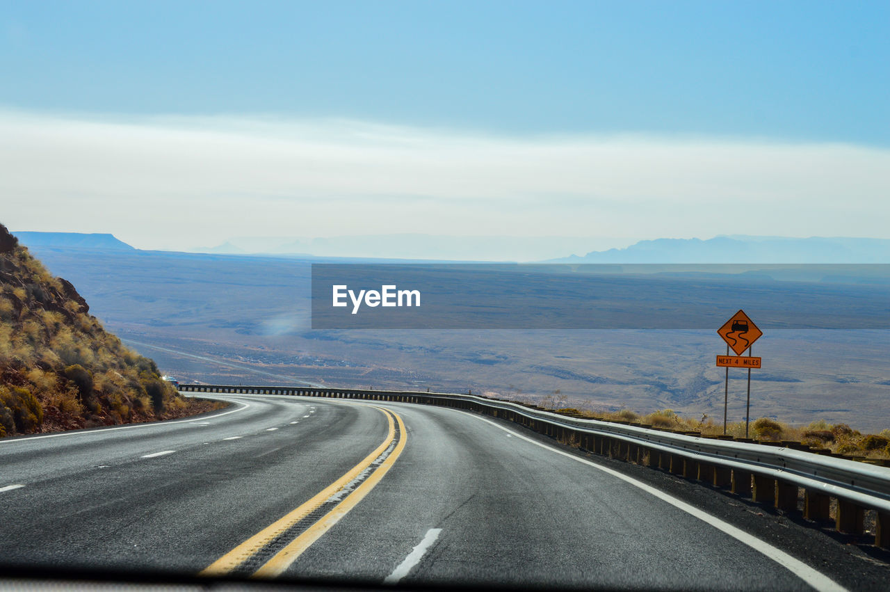 Empty road leading towards mountains against sky near arizona.