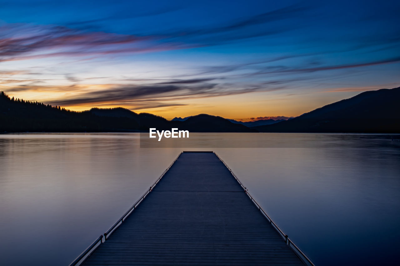 Pier over lake against sky during sunset