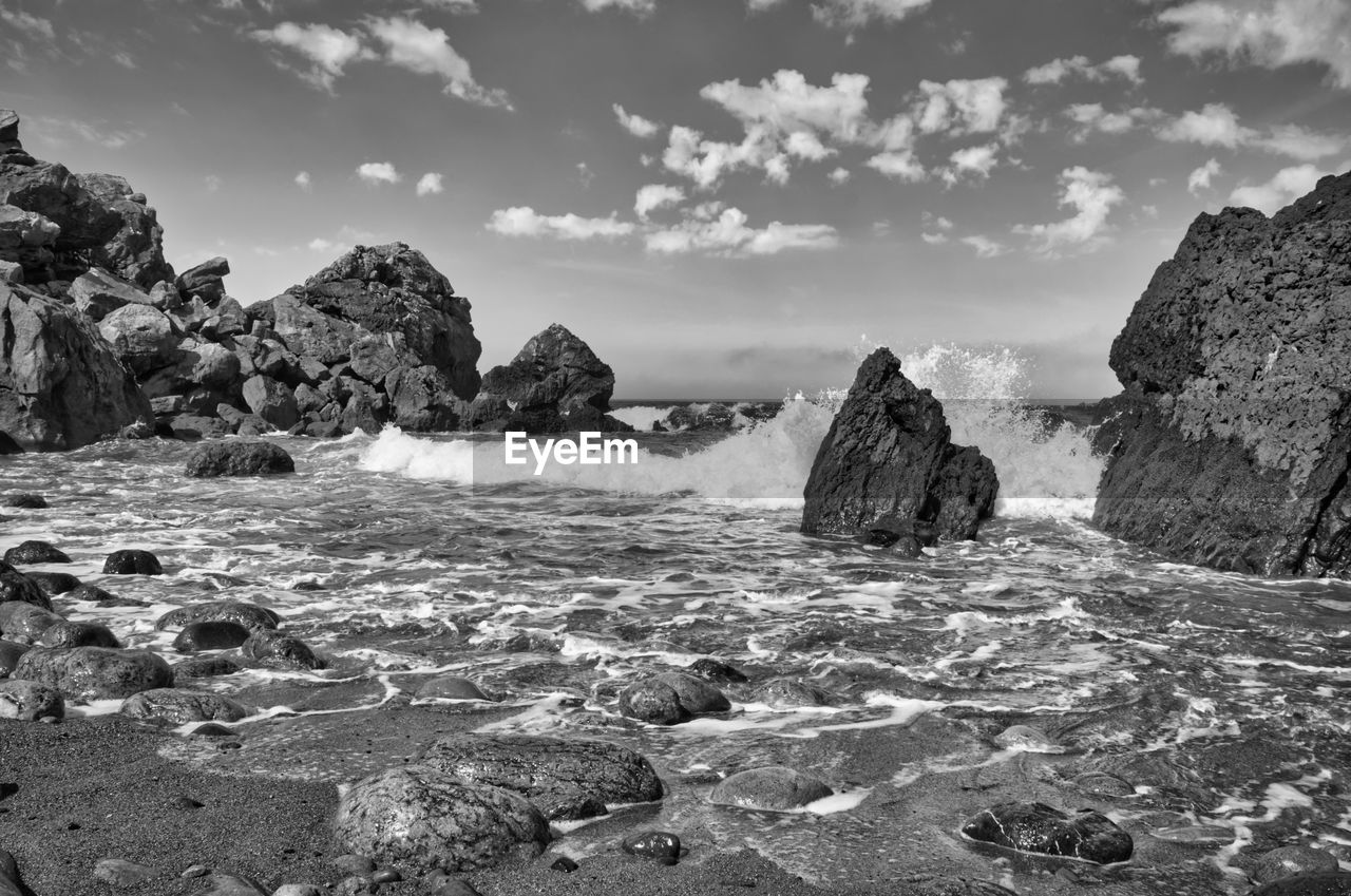 ROCKS ON SHORE AGAINST SKY