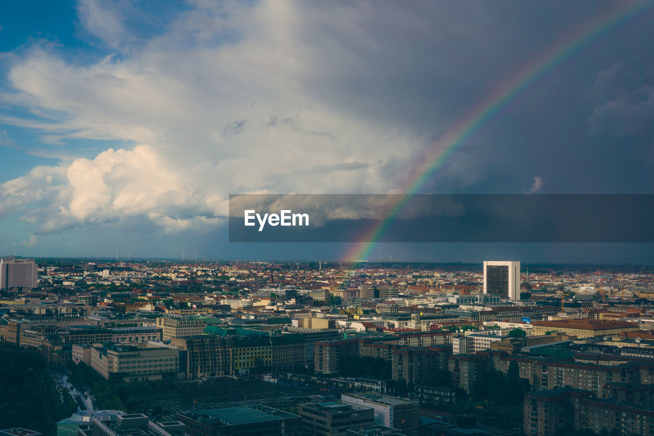Rainbow over cityscape against sky