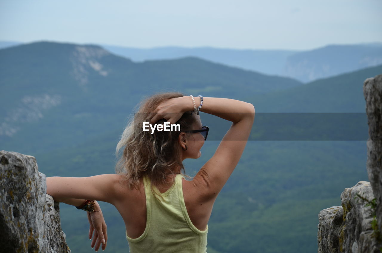 Woman standing on mountain against sky