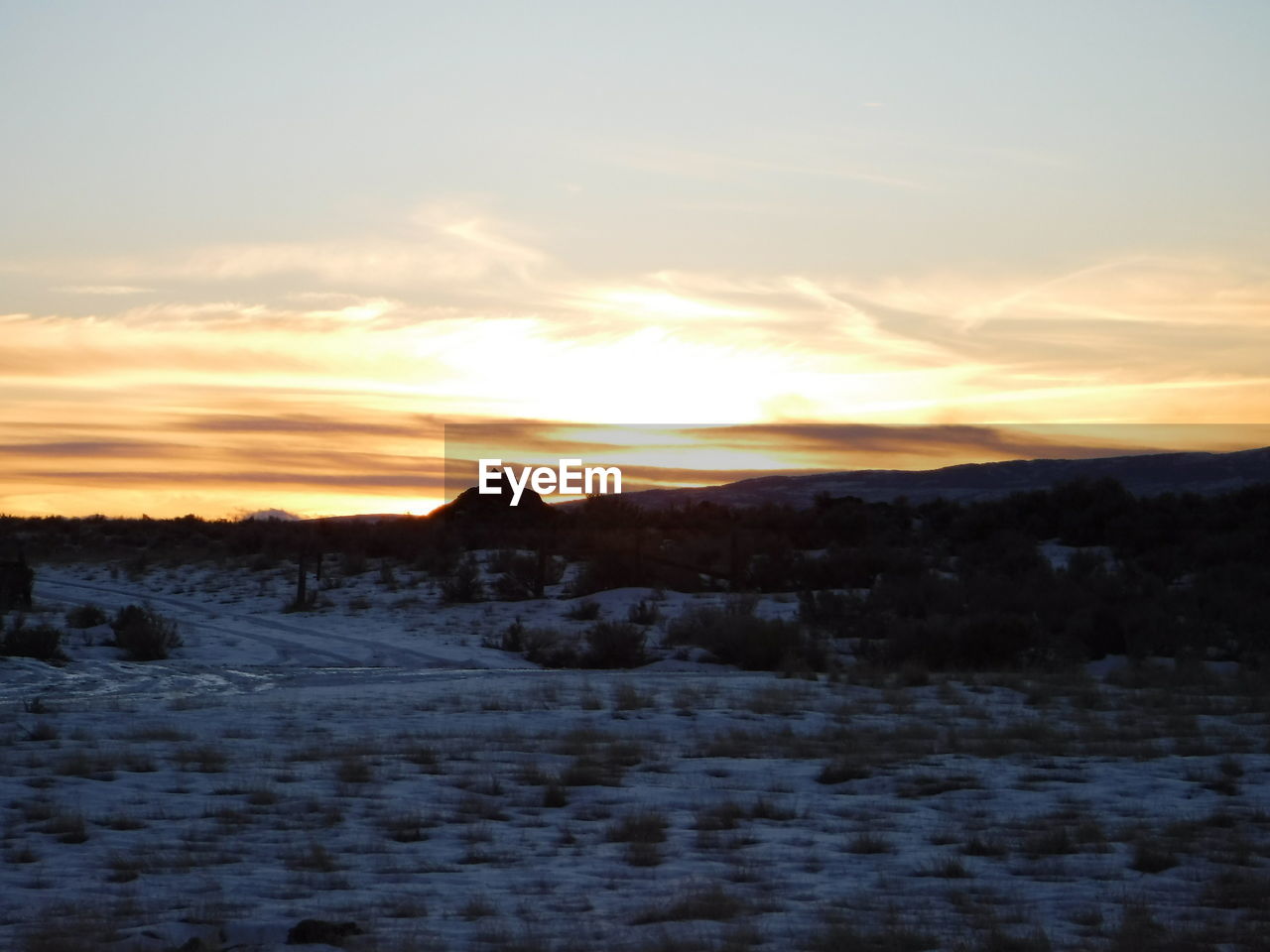 SNOW COVERED LAND AGAINST SKY DURING SUNSET
