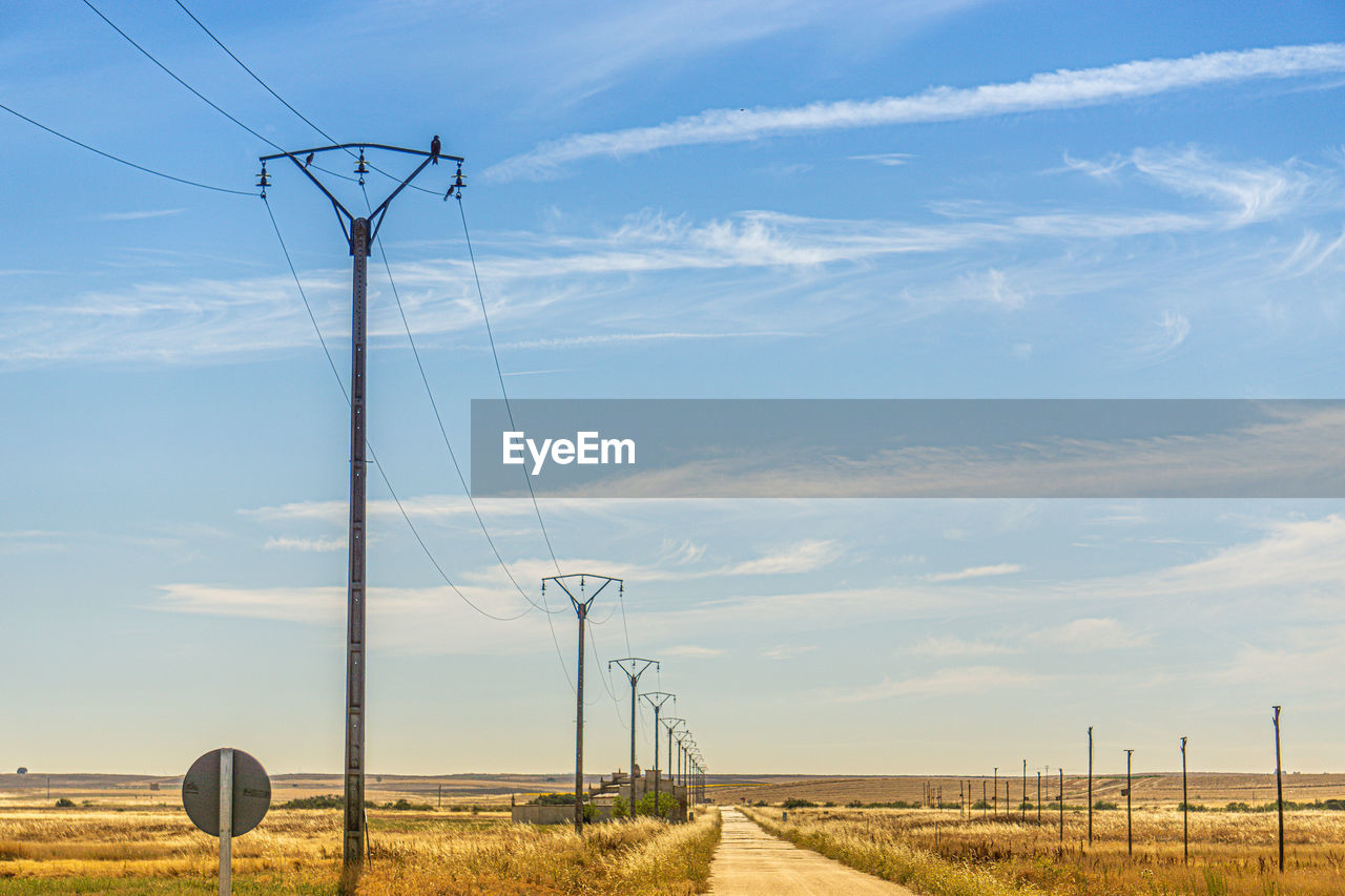 Electricity pylon on field against sky