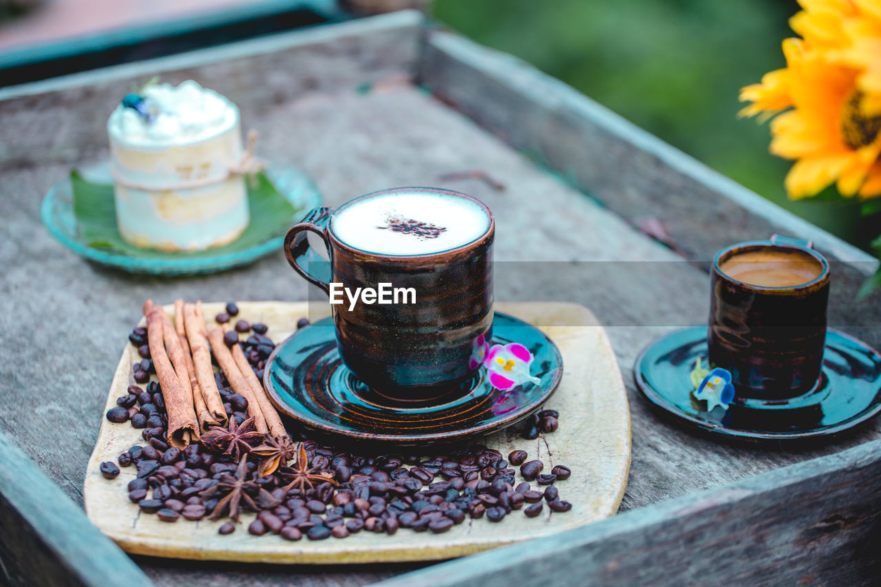 food and drink, drink, flower, blue, flowering plant, cup, coffee cup, freshness, coffee, saucer, mug, table, hot drink, crockery, food, refreshment, wood, nature, no people, plant, tea, outdoors, day, still life