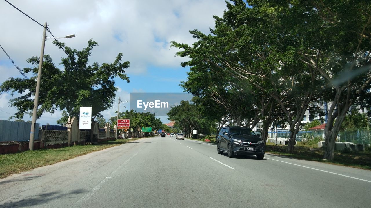 ROAD BY TREES AGAINST SKY