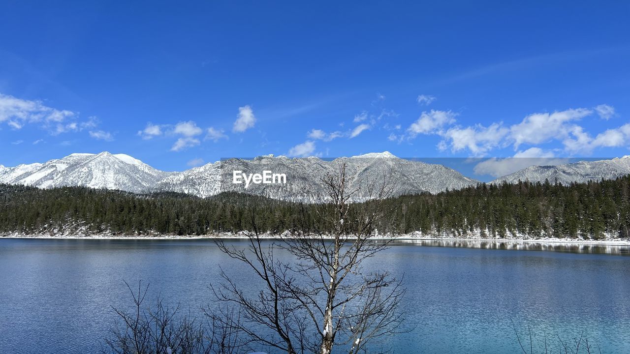 mountain, scenics - nature, beauty in nature, tree, sky, snow, lake, reflection, water, tranquil scene, mountain range, cold temperature, winter, tranquility, plant, nature, environment, no people, cloud, blue, landscape, forest, snowcapped mountain, wilderness, non-urban scene, pine tree, reservoir, day, coniferous tree, travel destinations, pinaceae, land, idyllic, pine woodland, travel, outdoors, body of water, tourism, remote