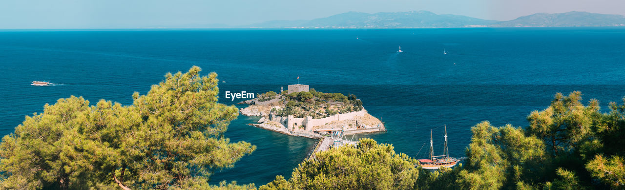 panoramic view of sea and trees against sky