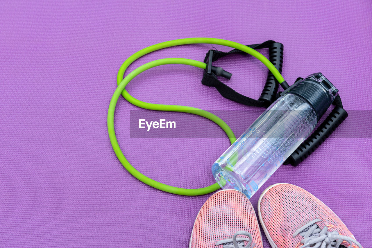 Sneakers, fit tube and a purple fitness mat. sport concept. copy-space