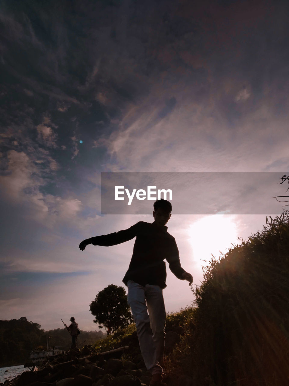 SILHOUETTE MAN STANDING ON FIELD AGAINST SKY AT SUNSET