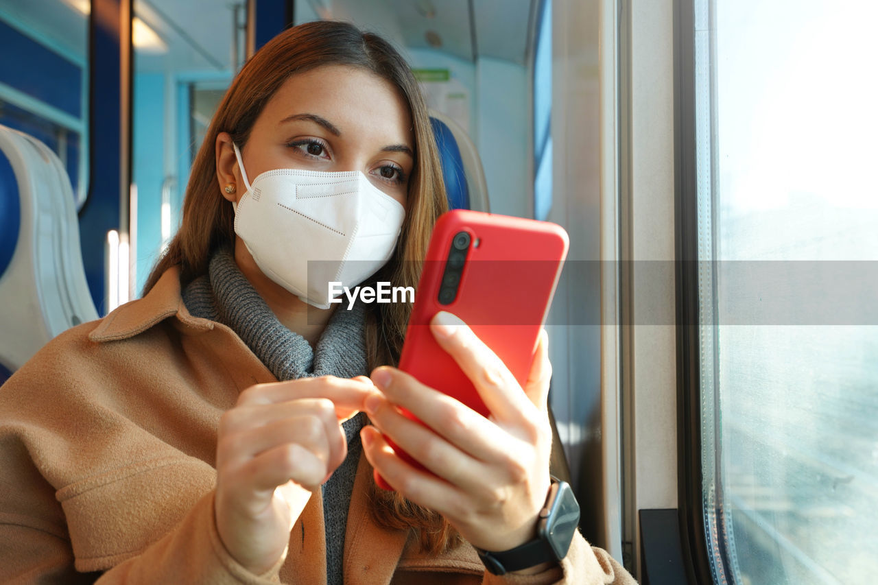 Safety on public transport. young woman with ffp2 kn95 face mask using mobile phone on train.