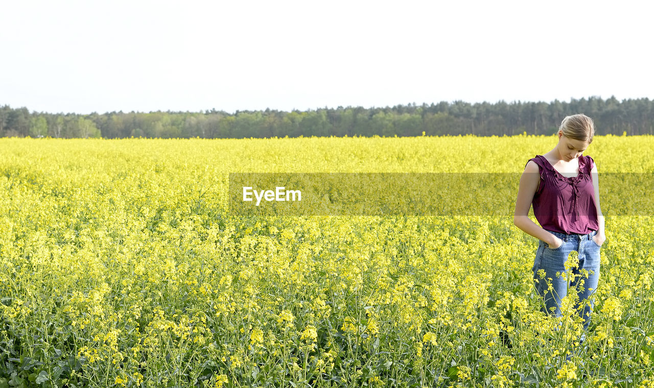 Woman standing amidst oilseed rape