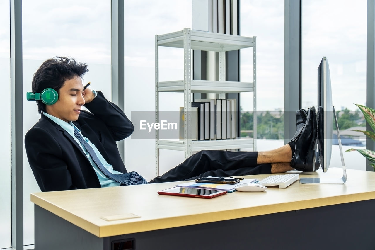 YOUNG WOMAN SITTING ON TABLE BY WINDOW AT OFFICE