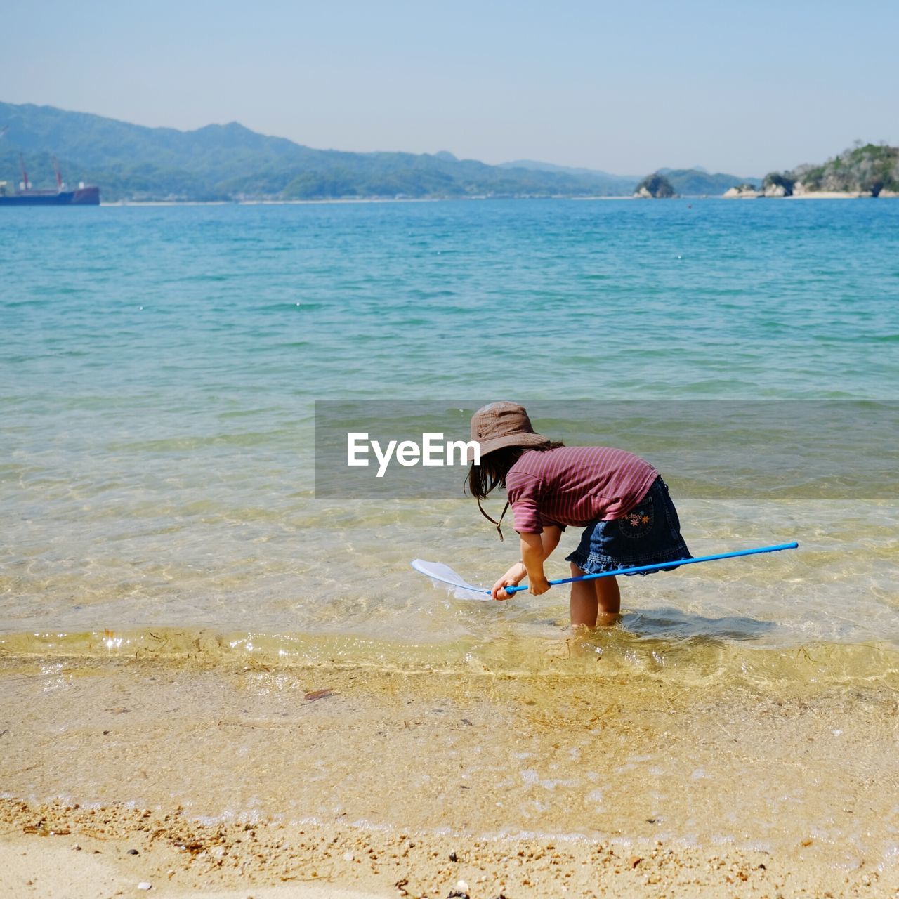 WOMAN ON BEACH AGAINST SEA