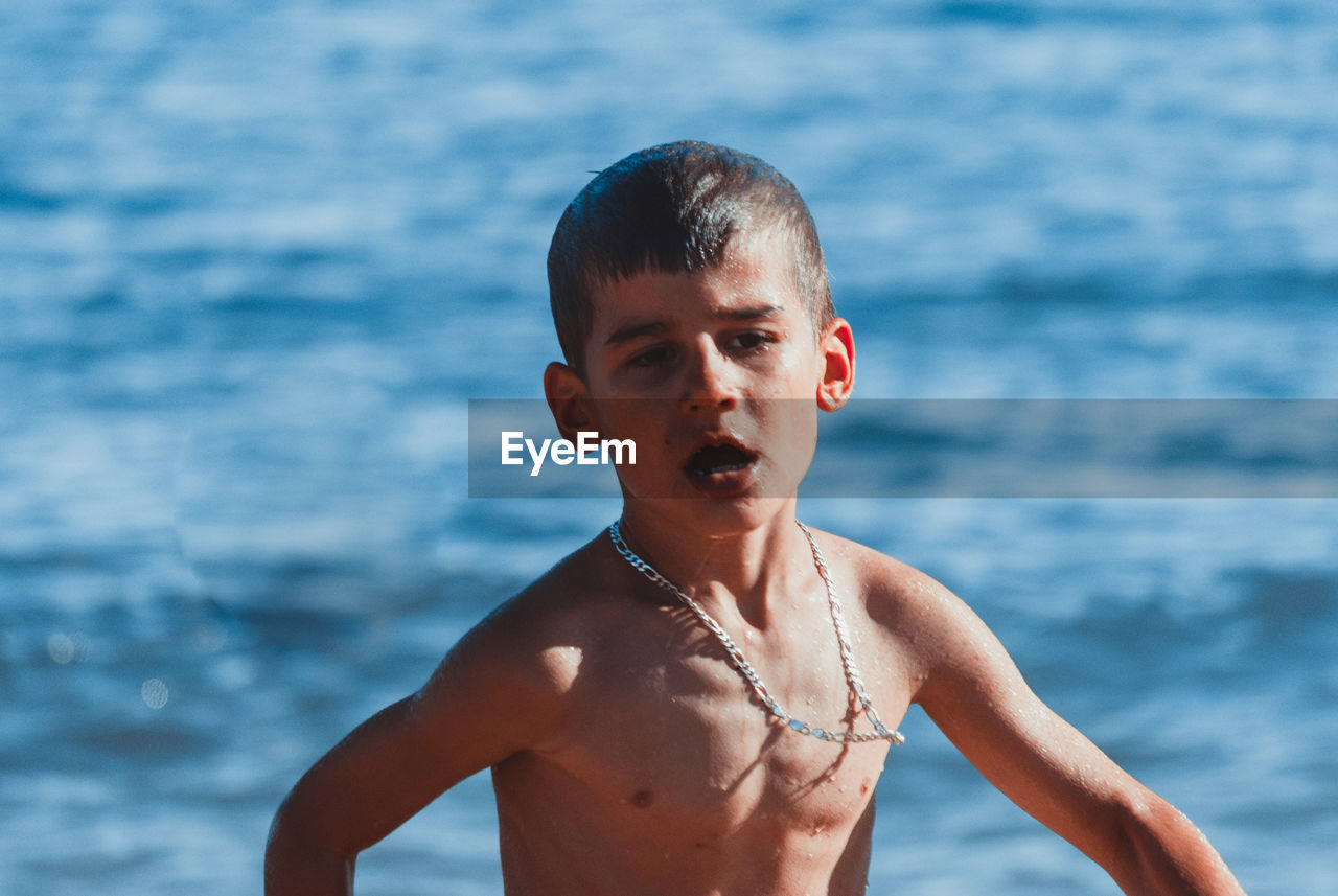 Shirtless boy walking against sea