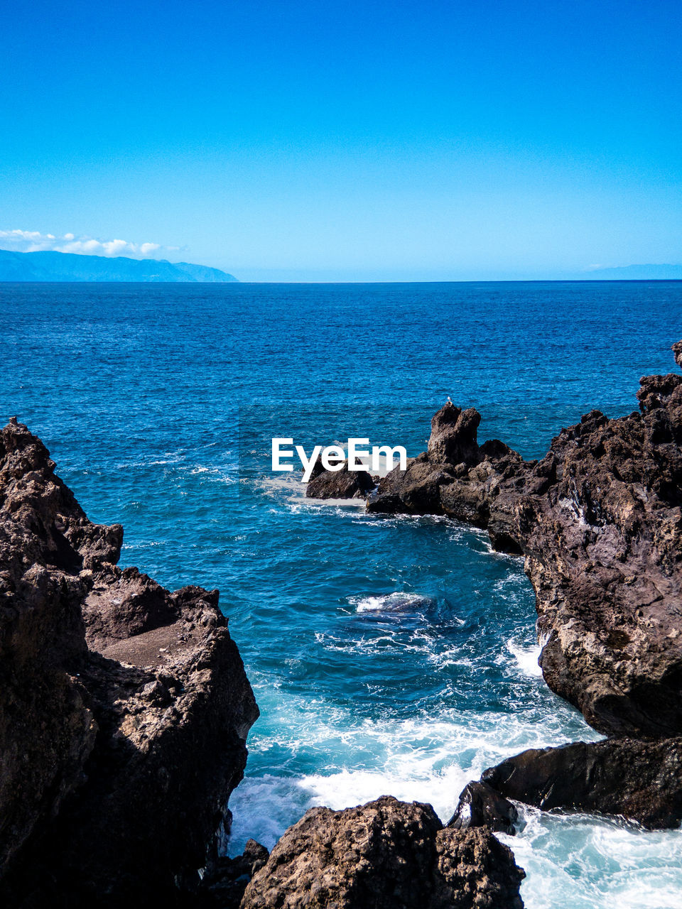 SCENIC VIEW OF ROCKY BEACH AGAINST SKY