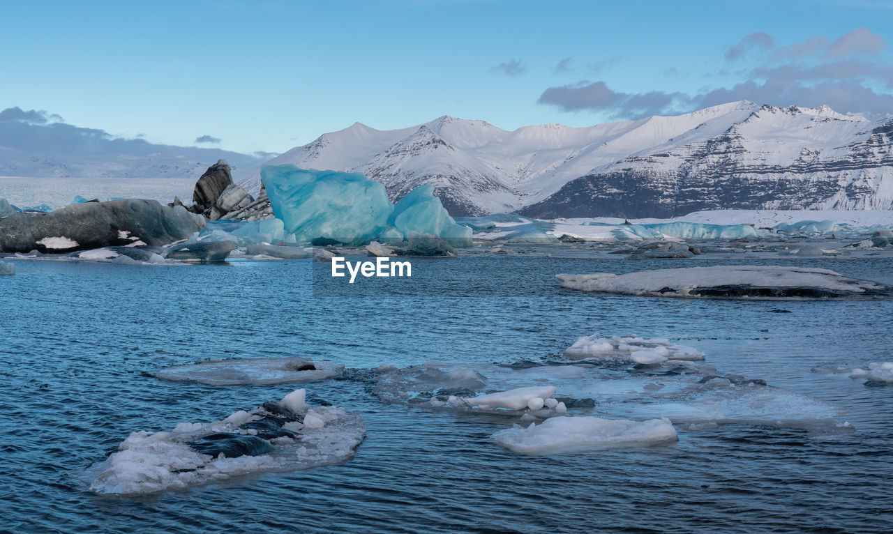 Icebergs in sea against sky during winter