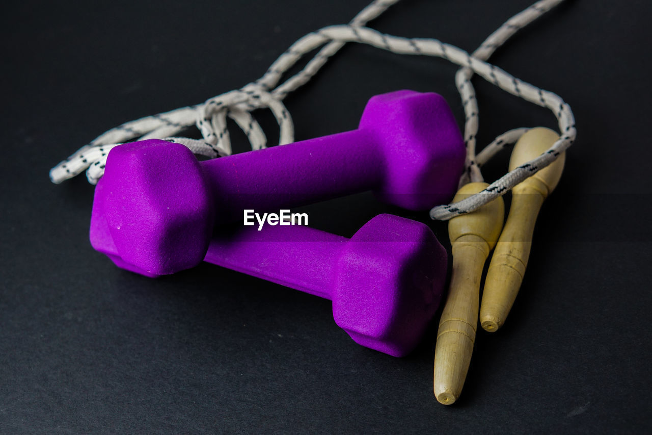 High angle view of dumbbells with jumping rope on black background