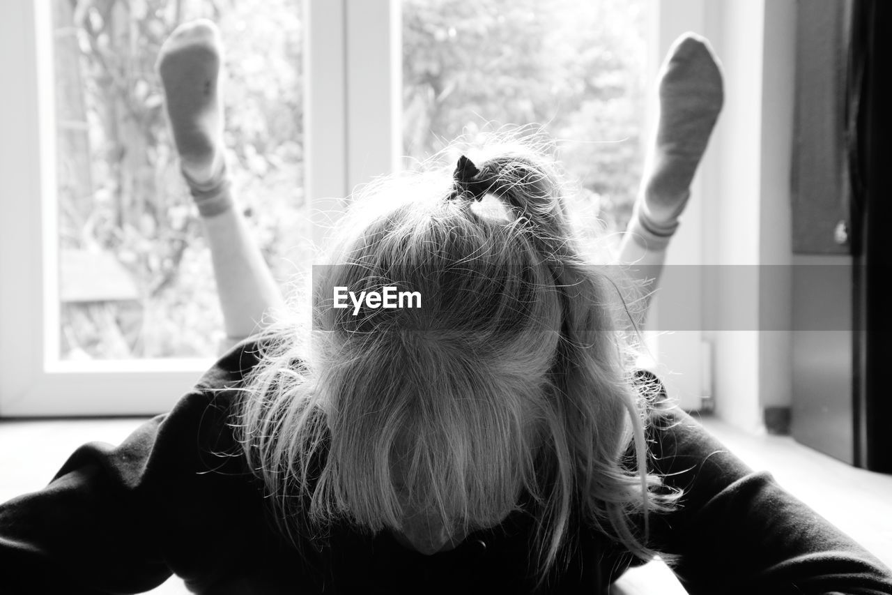 Rear view of woman looking at window at home