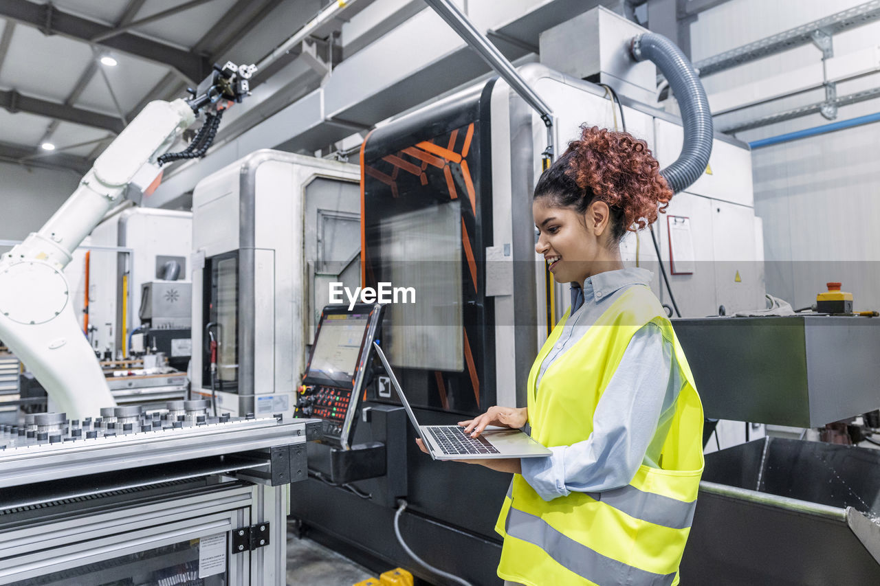 Happy engineer using laptop in factory