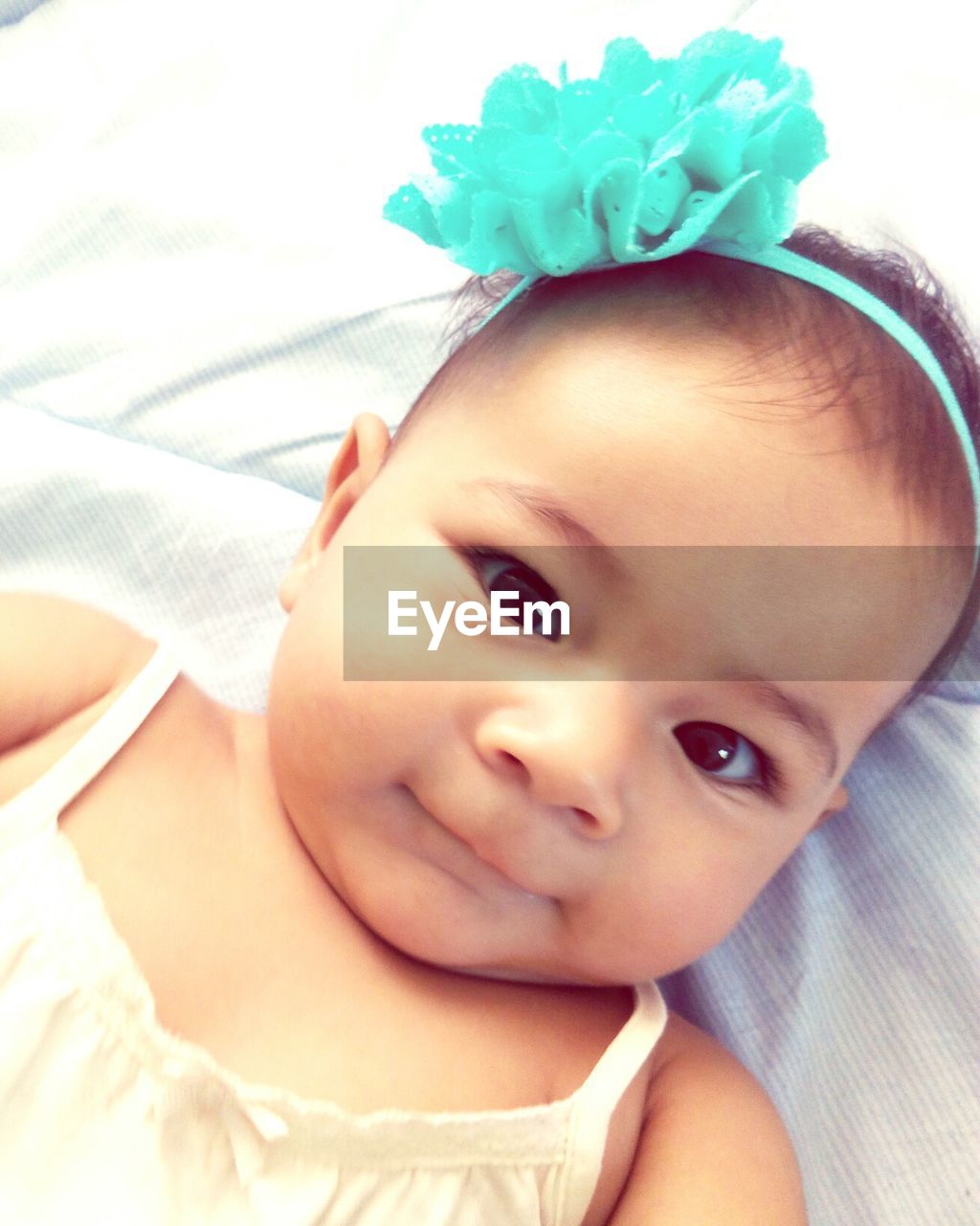 PORTRAIT OF CUTE BABY GIRL LYING ON BED