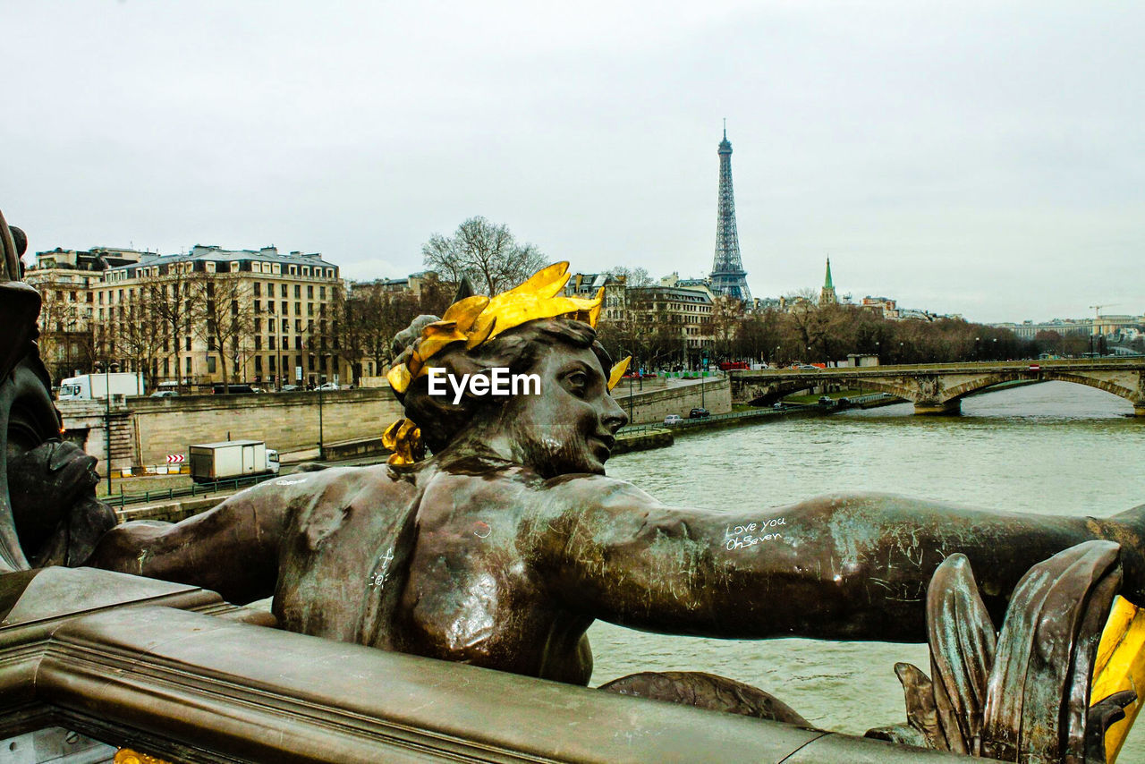 Statue at canal with eiffel tower in background