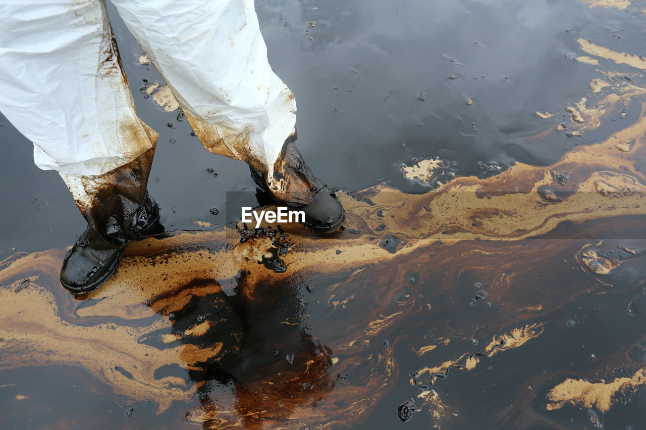 Low section of person standing on wet footpath