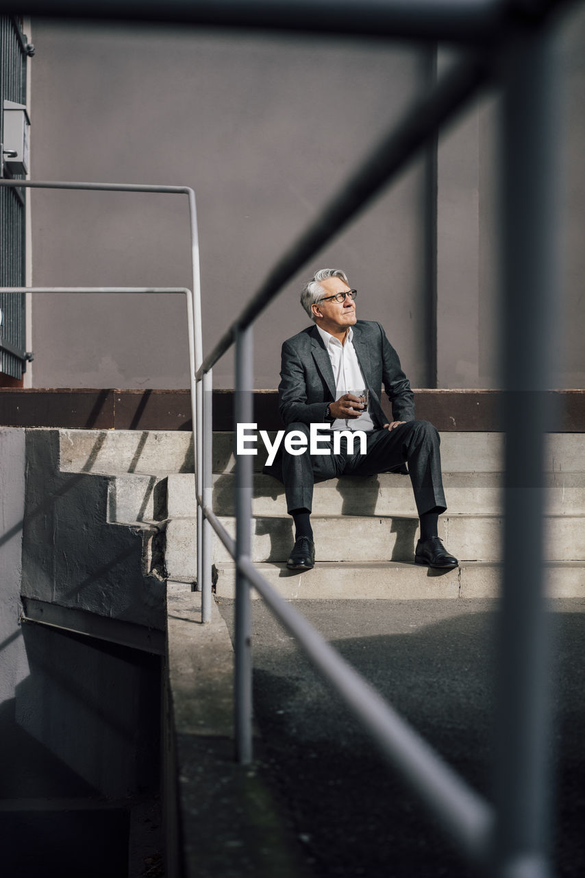 Senior businessman sitting on concrete stairs