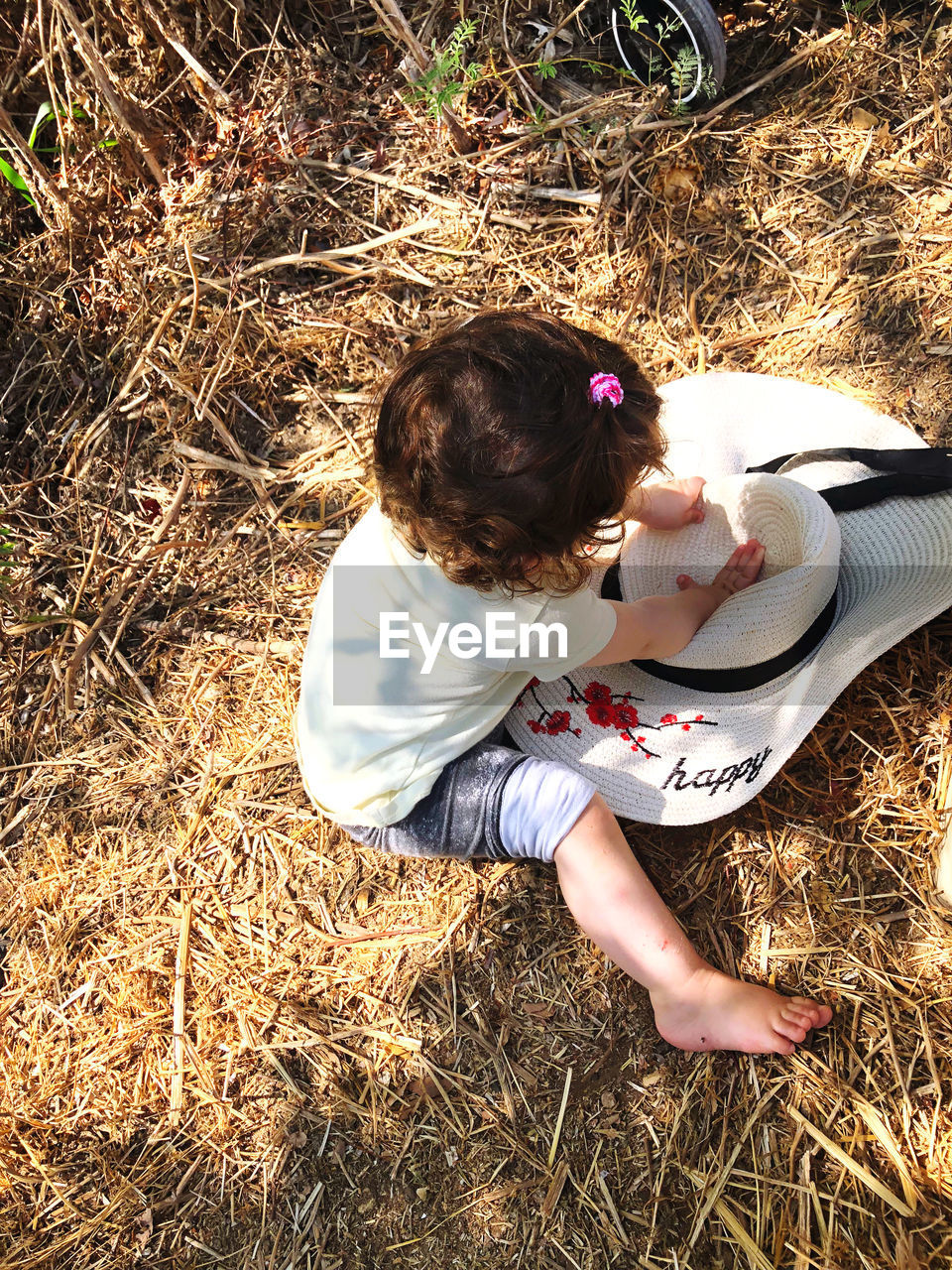 High angle view of girl with hat sitting on land