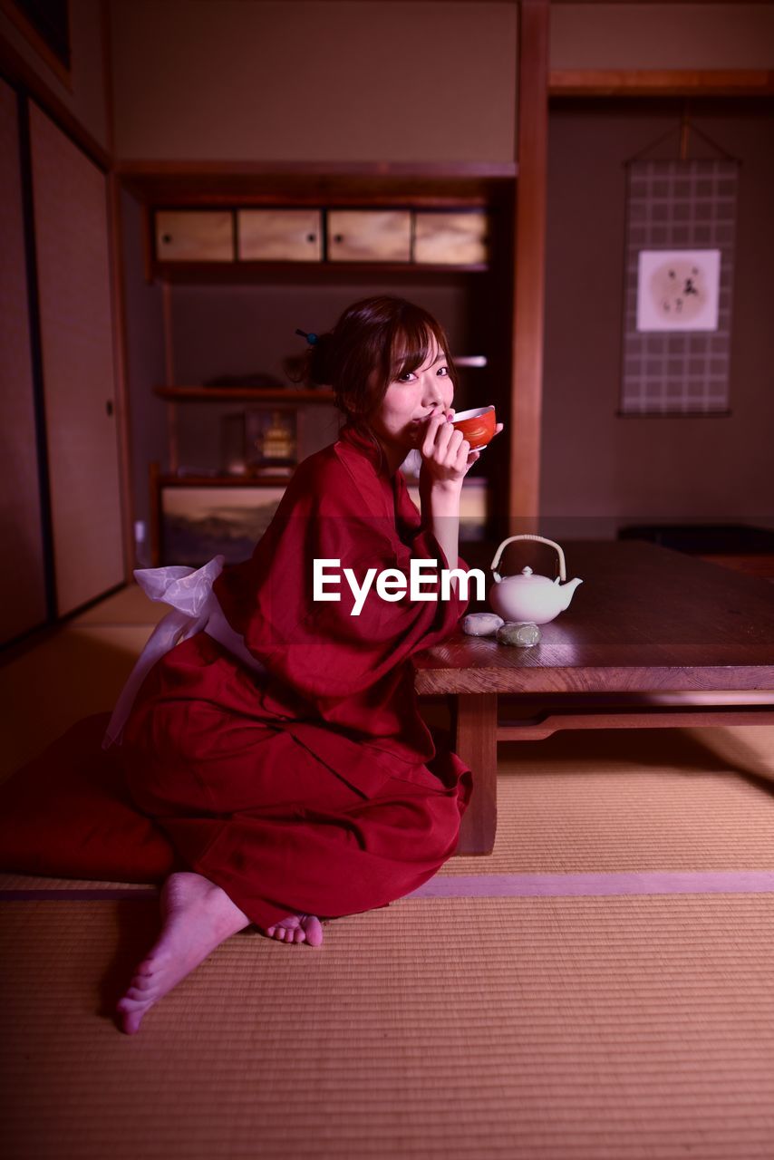 Woman looking away while sitting on table at home