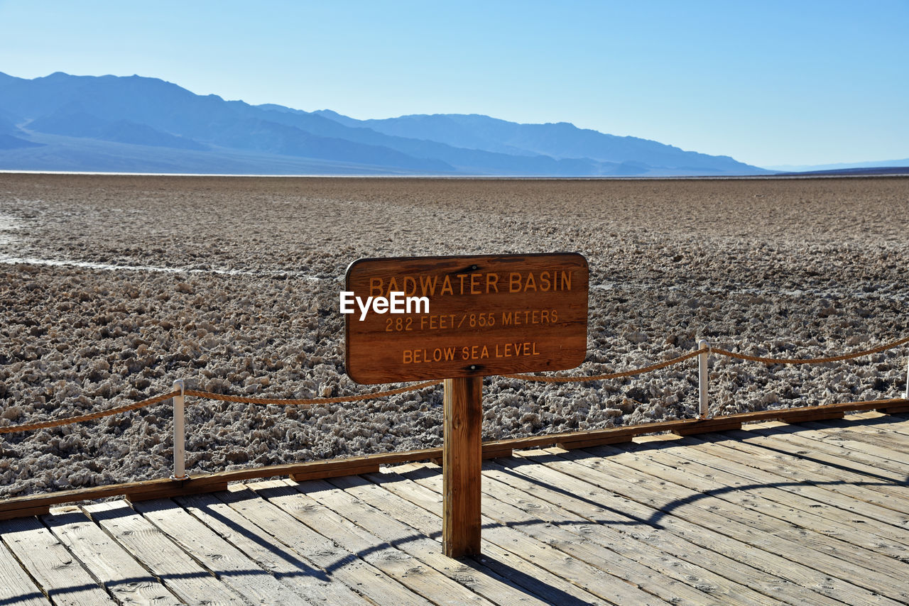 CLOSE-UP OF TEXT ON LANDSCAPE AGAINST MOUNTAIN RANGE