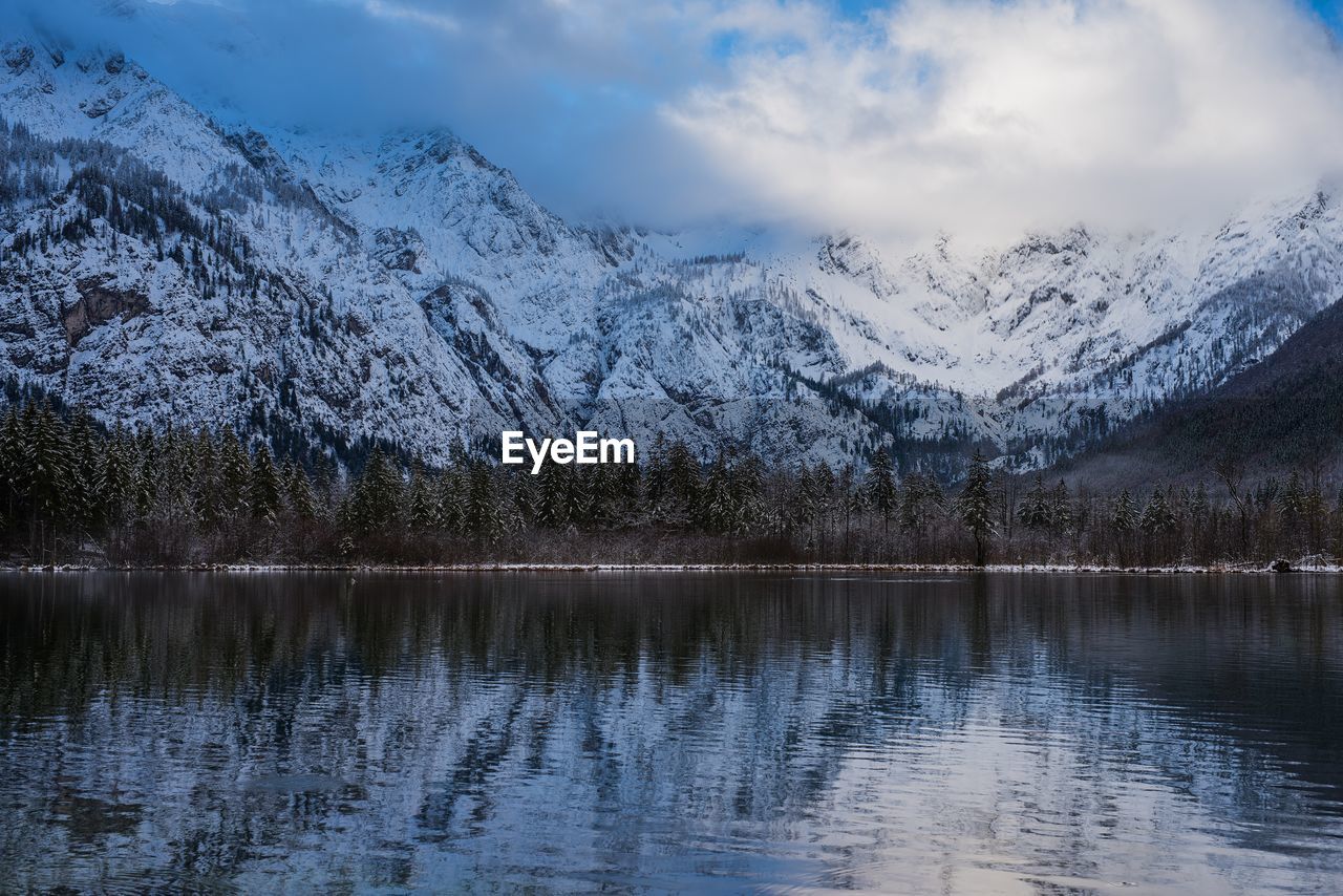 Scenic view of lake by snowcapped mountains against sky