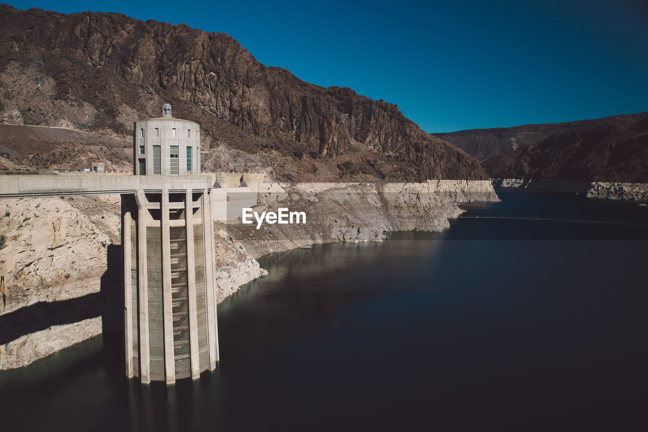 Hoover dam by colorado river against clear blue sky