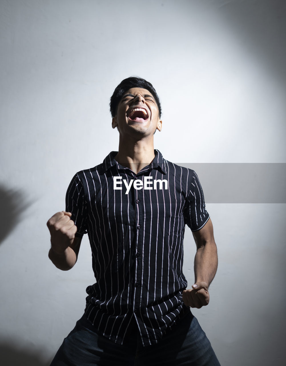 Dramatic portrait of a good looking handsome man in half shirt is winning hand.