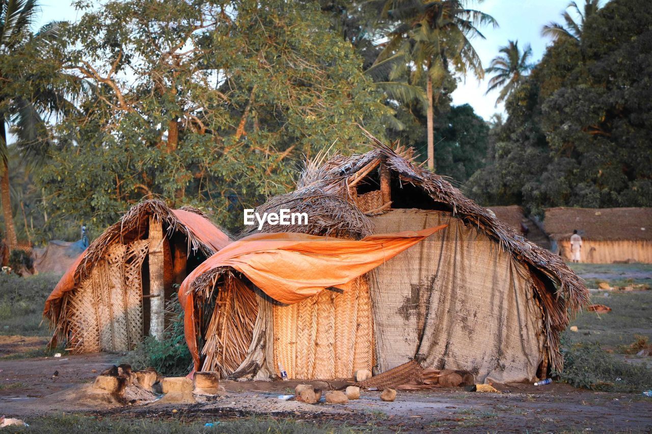 Huts on field against trees