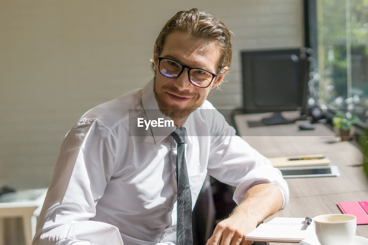 Portrait of young businessman wearing eyeglasses while sitting in office